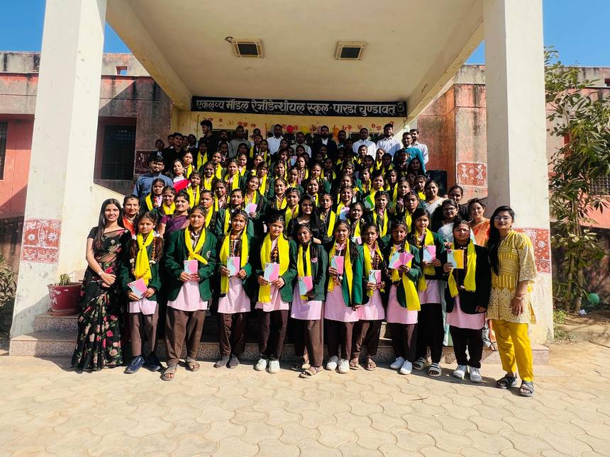 Students in sashes holding certificates on the school steps beneath the school name banner