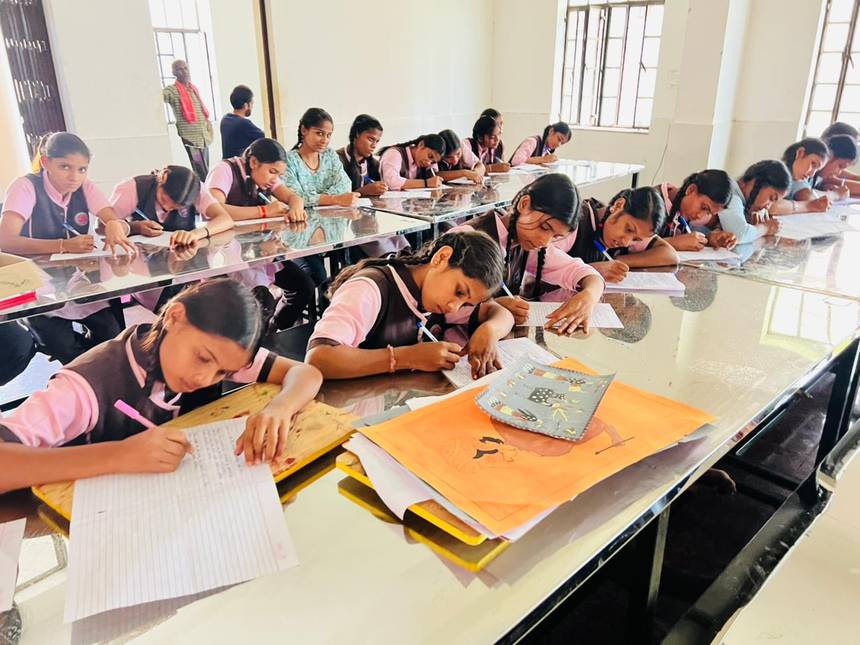 Students writing at long desks in a bright classroom of the school