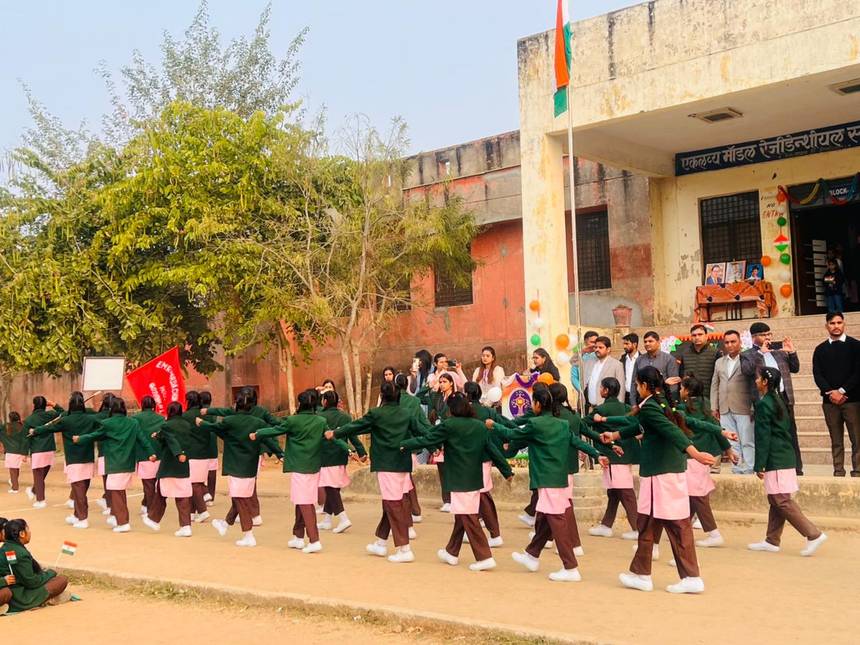 Students marching with the national flag in front of the school building