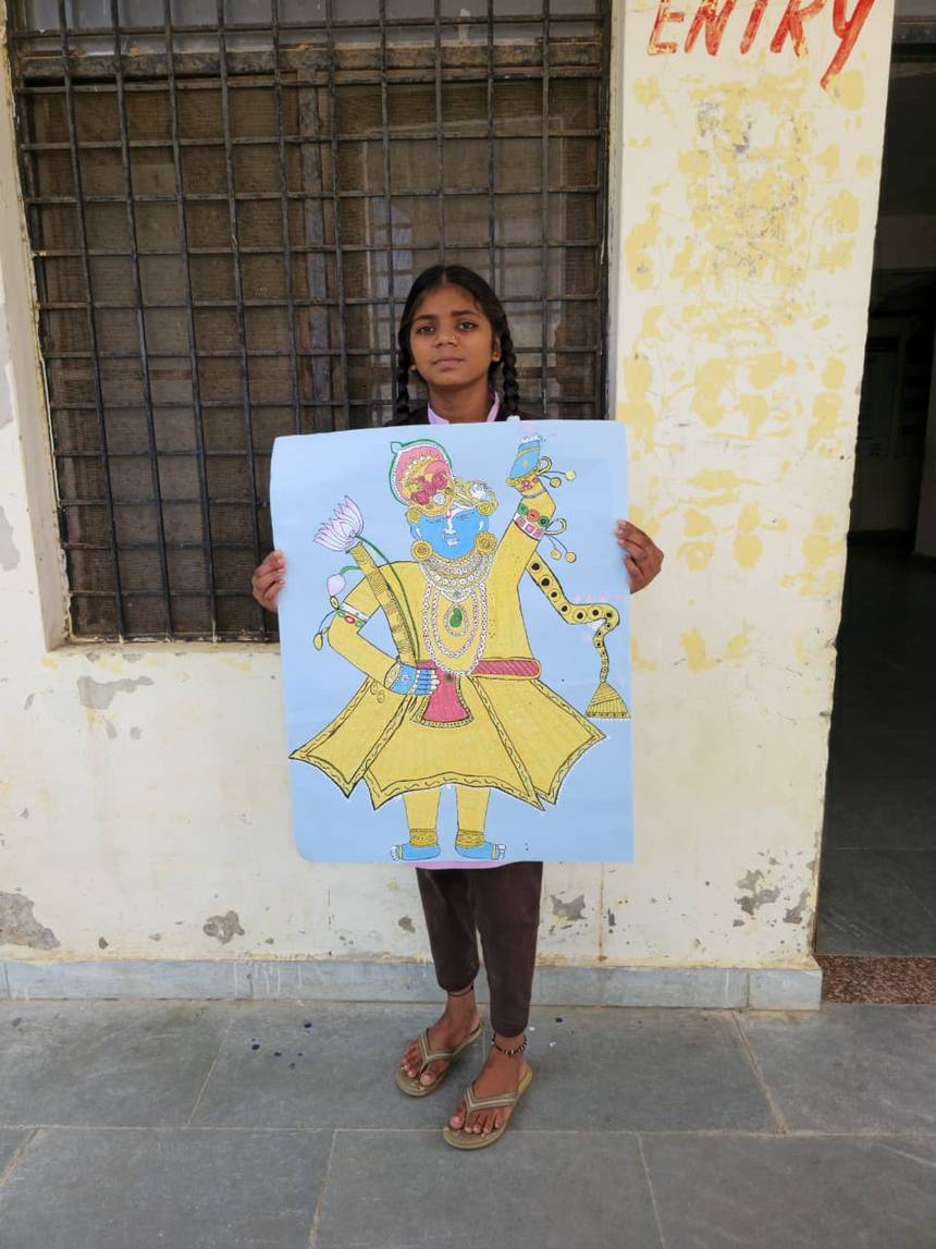 A student holding up her painting outside the school building