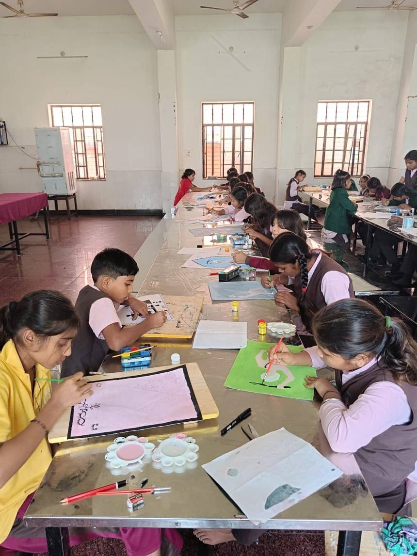 Students painting together at long tables in the school activity hall