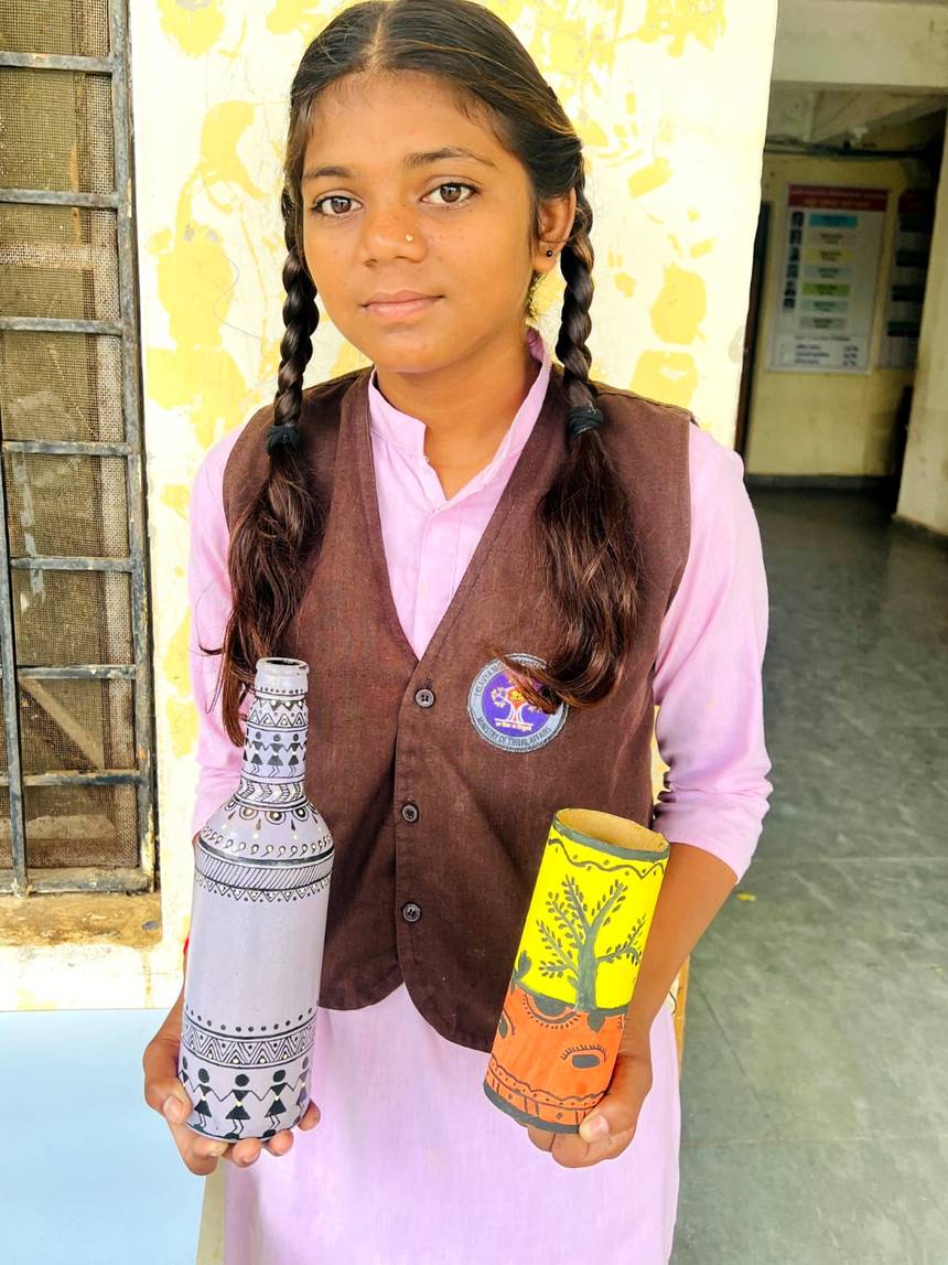 A student displaying hand painted craft work with tribal art motifs
