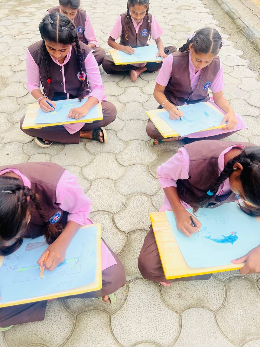 Students sitting on the ground sketching during an outdoor art activity