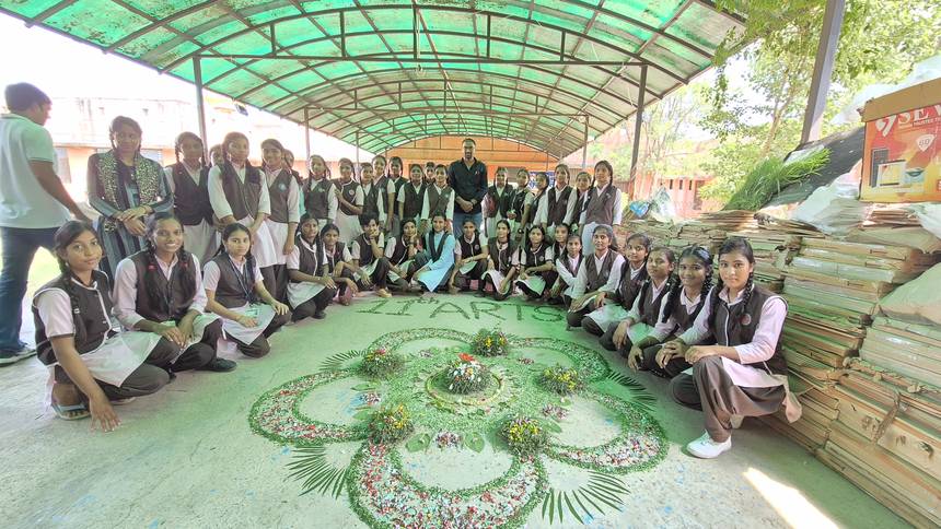 Students gathered around a leaf and flower floor design under the covered walkway
