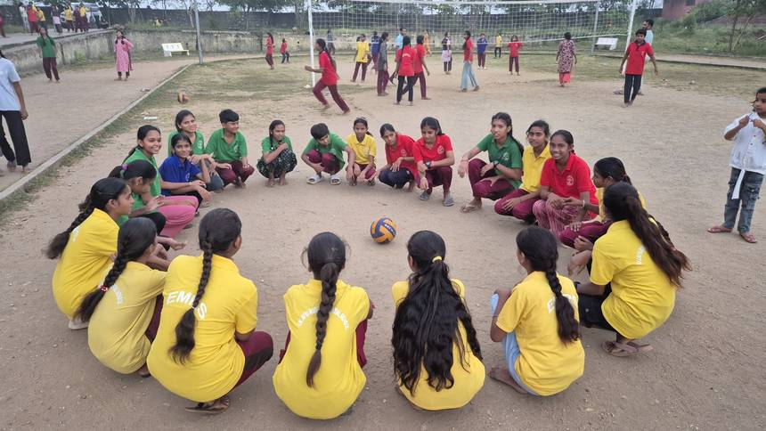 Students sitting in a circle on the ground during a games briefing